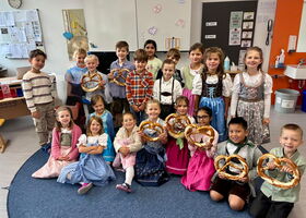 Gruppenbild in Tracht von einer Klasse, einige Kinder haben eine Riesenbreze in der Hand