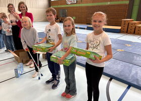 Schüler stehen in Reihe in der Turnhalle und haben Preise in der Hand