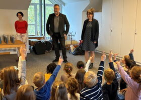 Schüler sitzen vor Bürgermeister am Boden und melden sich